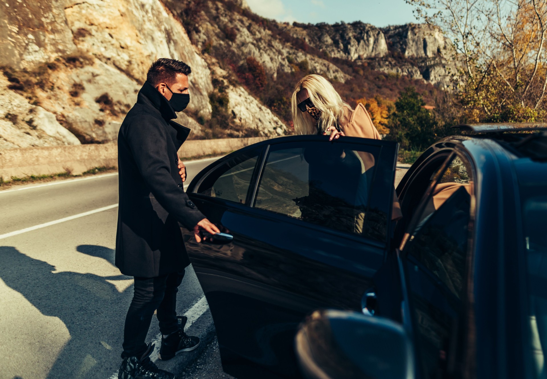 Chauffeur opens car door to businesswoman